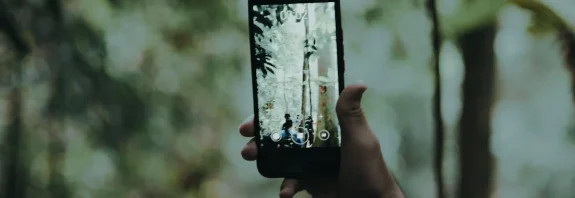 Seseorang memotret suasana hutan menggunakan kamera HP